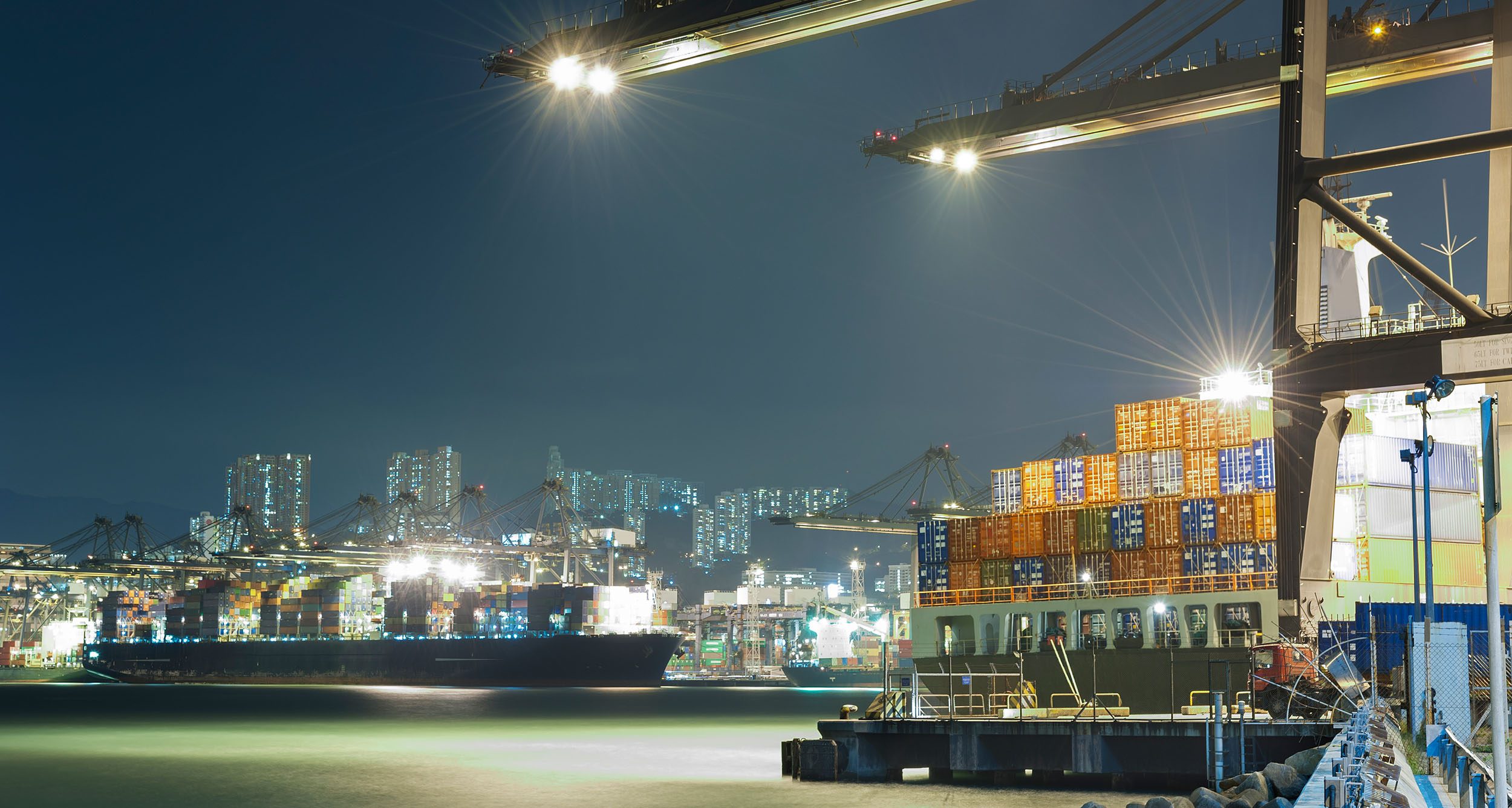 hell erleuteter Hafen bei Nacht, Schiffe, Kräne und Container